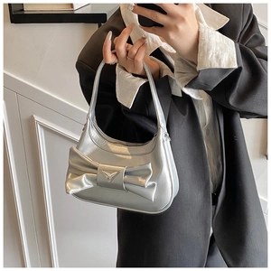 Close-up of a silver bow handbag with metallic finish and triangle metal buckle