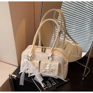 Detail of cream white shoulder bag featuring bow pockets and elegant lace pearl pendant