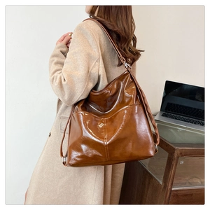Dettaglio di una grande borsa tote marrone lucida con doppie tasche e stile retrò