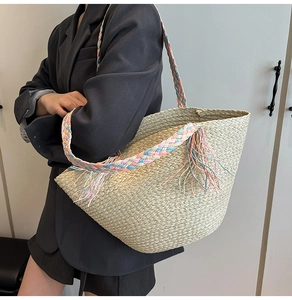 Dettaglio di una borsa in paglia beige con manici arcobaleno e nappe alla moda