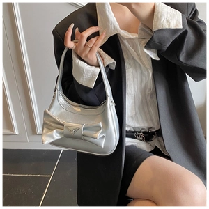 Detailed view of silver metallic bow handbag featuring a triangular plaque and Y2K style
