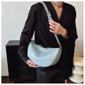 Close-up of light blue crescent bag featuring pebble leather texture and silver hardware