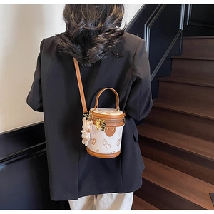 Detail of cylinder bucket bag with Teddy Bear print and plush charm on leather strap