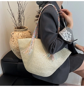 Dettaglio della borsa tote in paglia con manici intrecciati colorati e lunghe nappe
