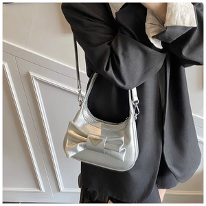 Detail of silver metallic crescent bag with large bow and triangular metal emblem