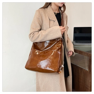 Dettaglio della borsa tote in pelle cerata lucida marrone indossata da una modella