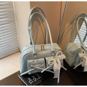 Detail view of light blue patent leather bag with bow pockets and pearl charm