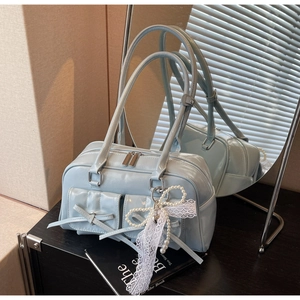 Detail of light blue glossy handbag with decorative bows and pearl lace pendant