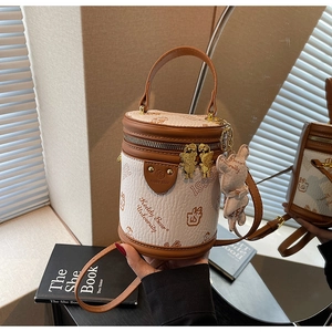 Detailed macro view of the two-tone cylinder bucket bag featuring metal bear zipper pull