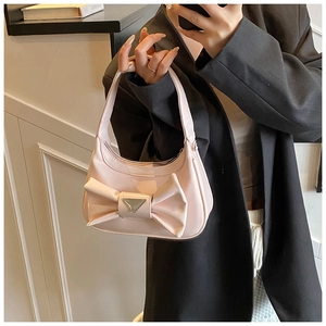 Detailed view of pink glossy bow handbag with signature silver triangular metal plaque