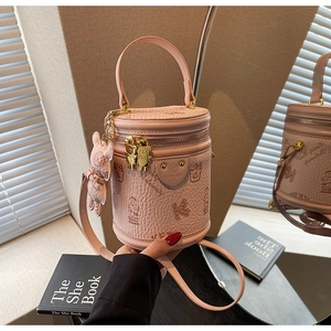 Detail of pink cylinder bucket bag with teddy bear pattern and golden hardware