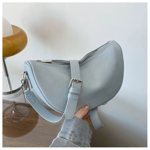 Macro view of light blue crescent bag with textured leather and silver buckle detail