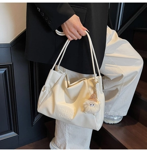 Detail of off-white oversized tote bag with MIKAXIQI logo and plush monster charm pendant