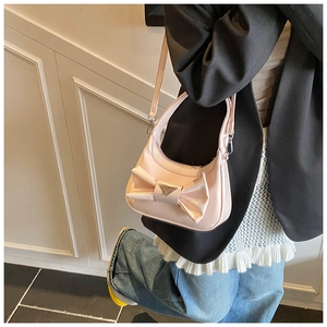 Detail of light pink satin handbag featuring a large bow and triangle metal buckle