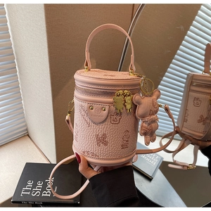 Detailed macro view of pink pebbled leather cylinder bag with bear embossing and gold hardware