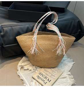 Dettaglio borsa di paglia con manici intrecciati colorati e nappe in stile boho