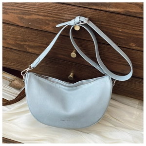Close-up of sky blue textured leather crescent bag with silver zipper and brand logo