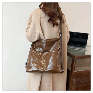 Borsa tote in pelle lucida marrone indossata sulla spalla in un interno elegante