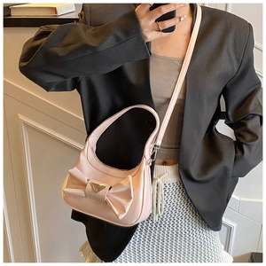Detailed view of pink shoulder bag with large bow and silver triangular metal emblem