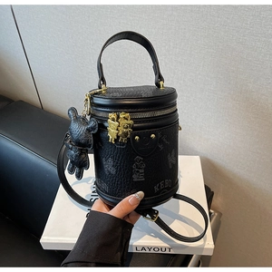 Detail view of black cylindrical bucket bag with bear print and golden zipper