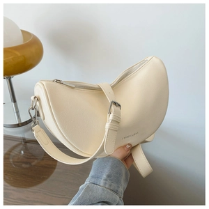 Detail of cream half-moon crossbody bag with silver hardware and smooth leather texture