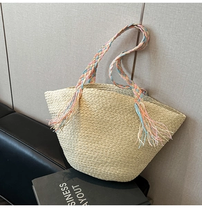 Dettaglio della borsa tote in paglia beige con tracolla intrecciata a nappe colorate