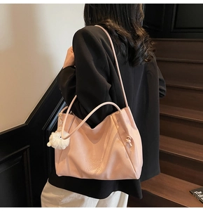 Detail of pink faux leather tote bag featuring plush charm and stylish side drawstrings