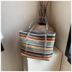 Detail of colorful striped woven tote bag with silver trim on a minimalist display stand