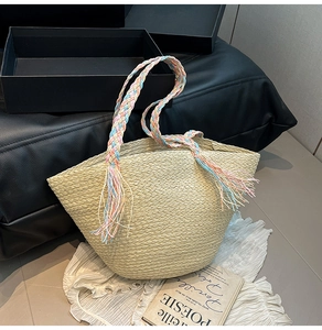 Dettaglio della borsa tote in paglia con manici intrecciati colorati e nappe vivaci