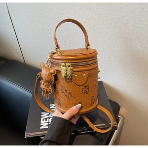 Detail shot of brown cylinder bag with teddy bear print and cute bear charm accessory