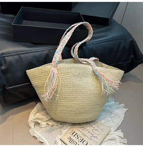 Dettaglio della borsa tote in paglia con manici in nastro colorato e accenti di frange