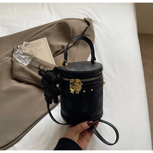 Detailed close-up of a black cylinder bucket bag with golden bear zippers and a bear charm