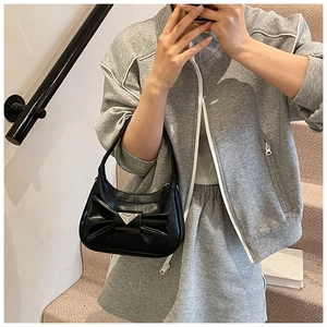 Detail of black bow handbag with silver triangular metal piece on synthetic leather