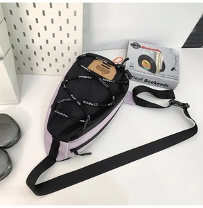 Détail du sac de poitrine bicolore avec cordon élastique imprimé et logo en similicuir