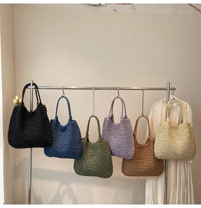 Detail view of woven tote bags in six colors hanging on a minimalist metal rack