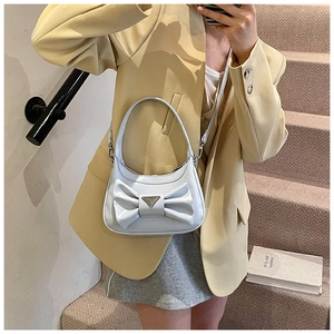Detail of light blue patent leather bag with a large bow and metallic triangle clasp