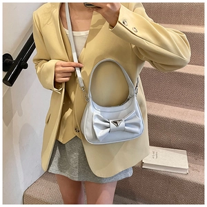 Detail of light blue bow handbag with triangular buckle on a fashion model