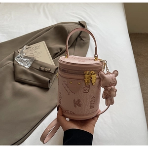 Detailed view of pink cylindrical bucket bag with vintage bear patterns and charms