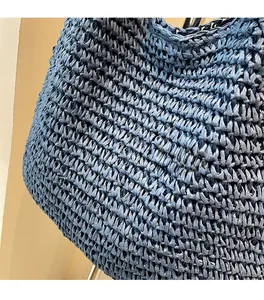 Close-up of the intricate dark blue crochet weave and soft texture on the straw beach bag