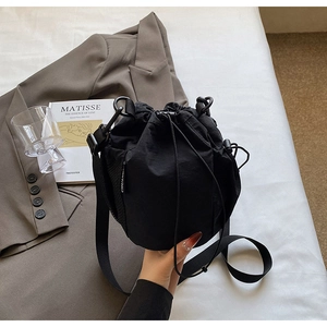 Detail der schwarzen Kordelzug-Beuteltasche mit verstellbarem Gurt und urbanem Utility-Stil