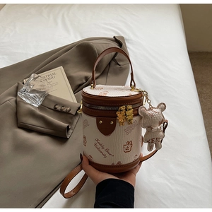 Detail of cylindrical bucket bag with brown leather trim and vintage bear print mascot
