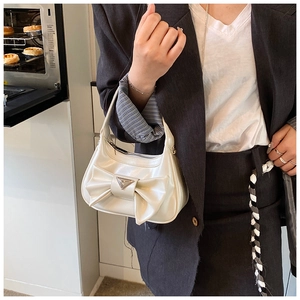 Chic cream bow handbag with silver triangular plaque shown in a lifestyle home setting