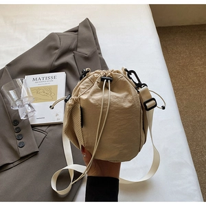 Detail der beigen Nylon-Beuteltasche mit seitlicher Netztasche und verstellbarem Gurt
