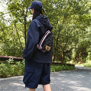 Look extérieur du sac bandoulière noir et rose porté avec une veste de sport