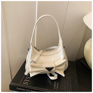 Detail of cream white crescent bag with oversized bow and silver triangular logo
