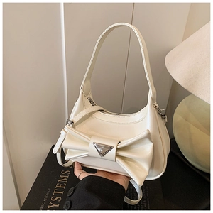 Macro detail of white leather handbag featuring a stylish bow and metal triangle logo