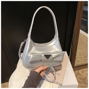 Detail of silver crescent handbag featuring large bow and triangle metal emblem