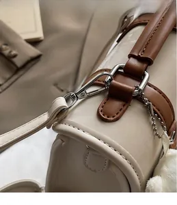 Detail of silver metal lobster clasp and clean stitching on a stylish cream shoulder bag