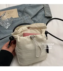 Detail view of the drawstring front pocket on a cream crossbody bag for easy storage
