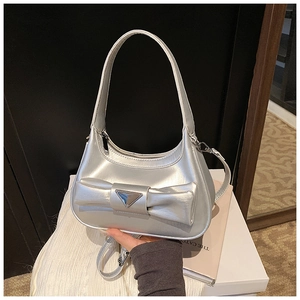 Detail of silver metallic handbag featuring large bow design and triangle metal plaque